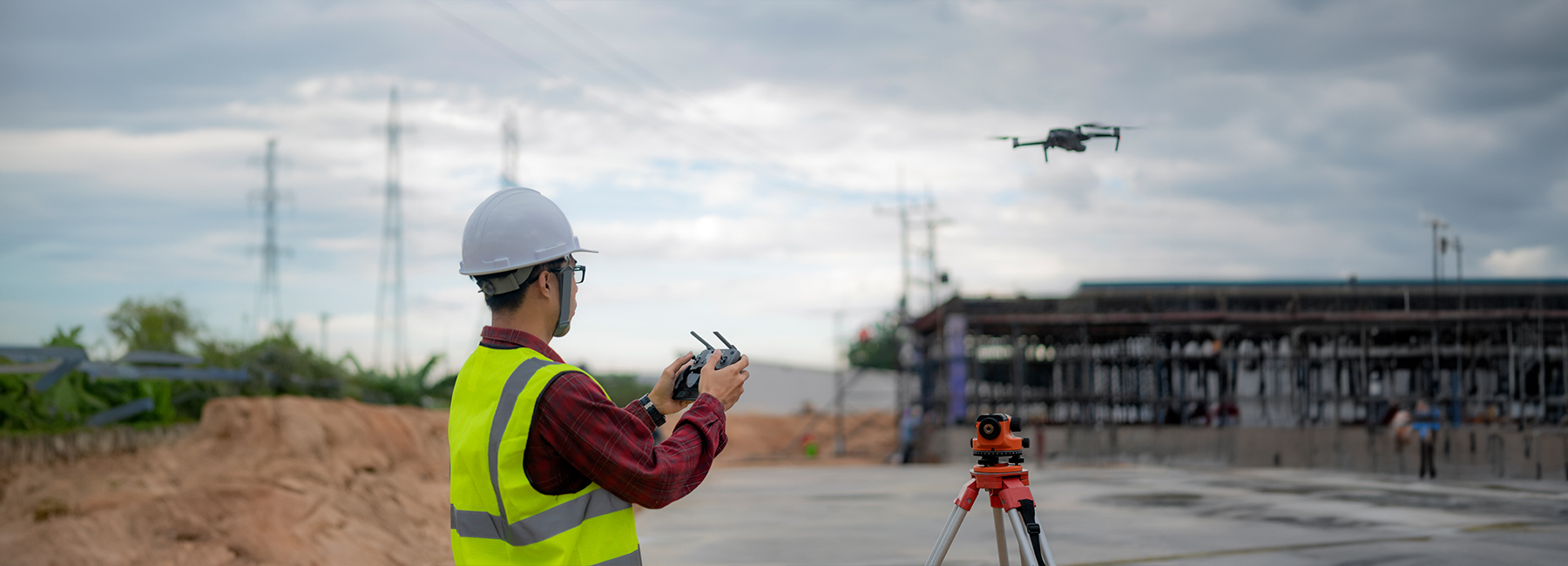 Asian construction worker piloting drone at building site.